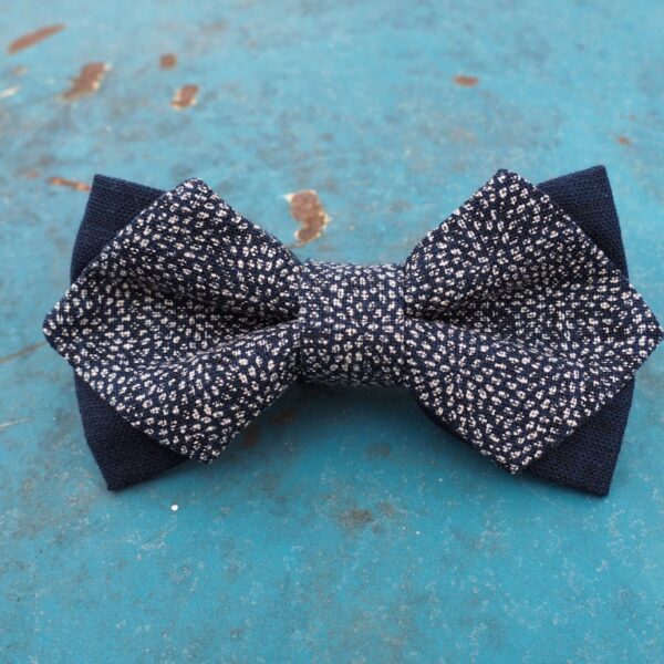 Tummansininen rusetti, jossa on pieniä vaaleita pistekuvioita, asetettuna kuluneen turkoosin pinnan päälle.