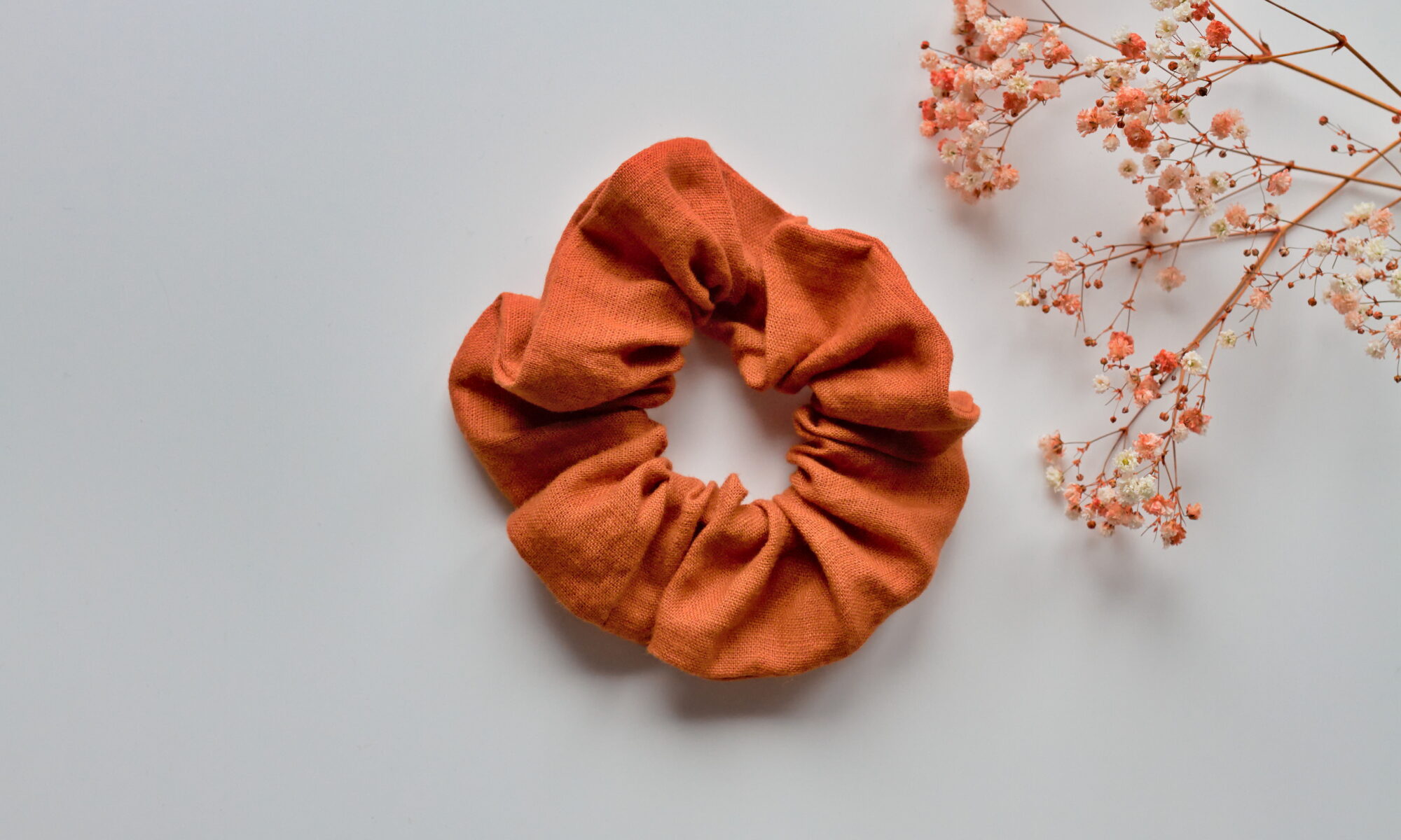 Kuvassa valkoista taustaa vasten pellavainen oranssin sävyinen hiusdonitsi.