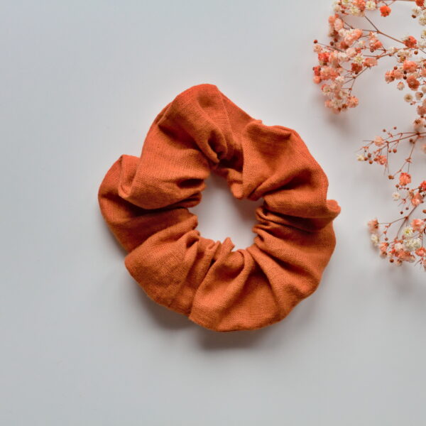 Kuvassa valkoista taustaa vasten pellavainen oranssin sävyinen hiusdonitsi.