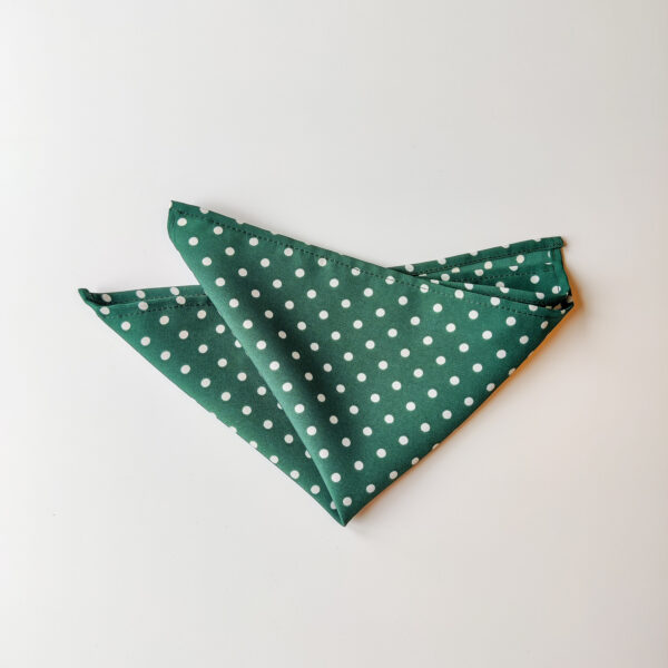 Kuvassa tumman vihreä valkoisilla pilkuilla taiteltu taskuliina